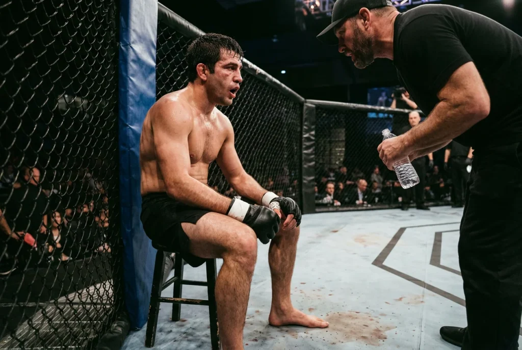 Trainer und MMA-Kämpfer in der Octagon-Ecke zwischen den Runden
